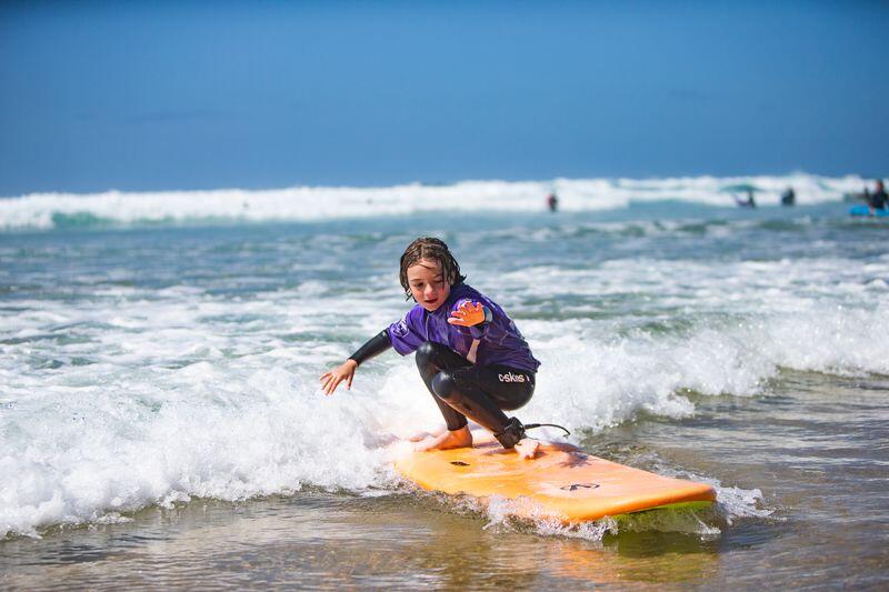Child catching a wave during a surf lesson with Wavehunters
