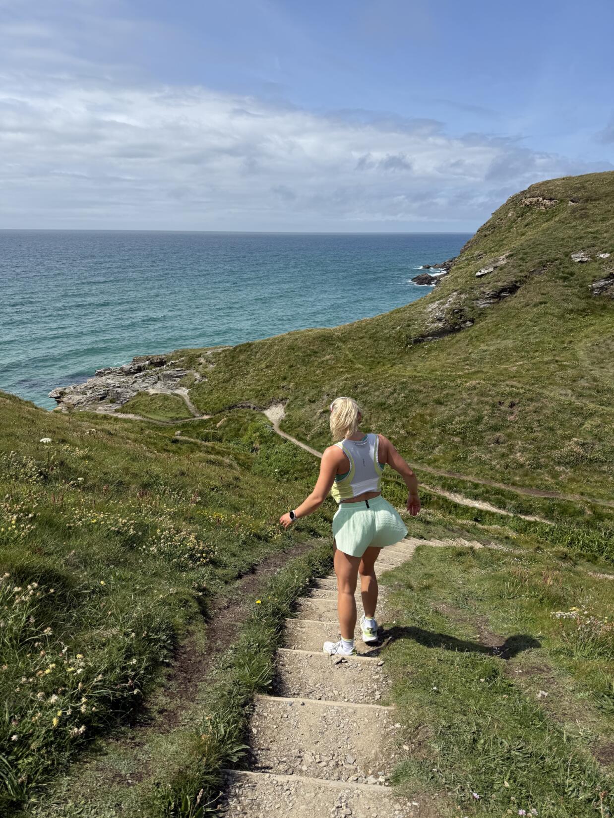 Girl in active wear running the coast path in Newquay Cornwall
