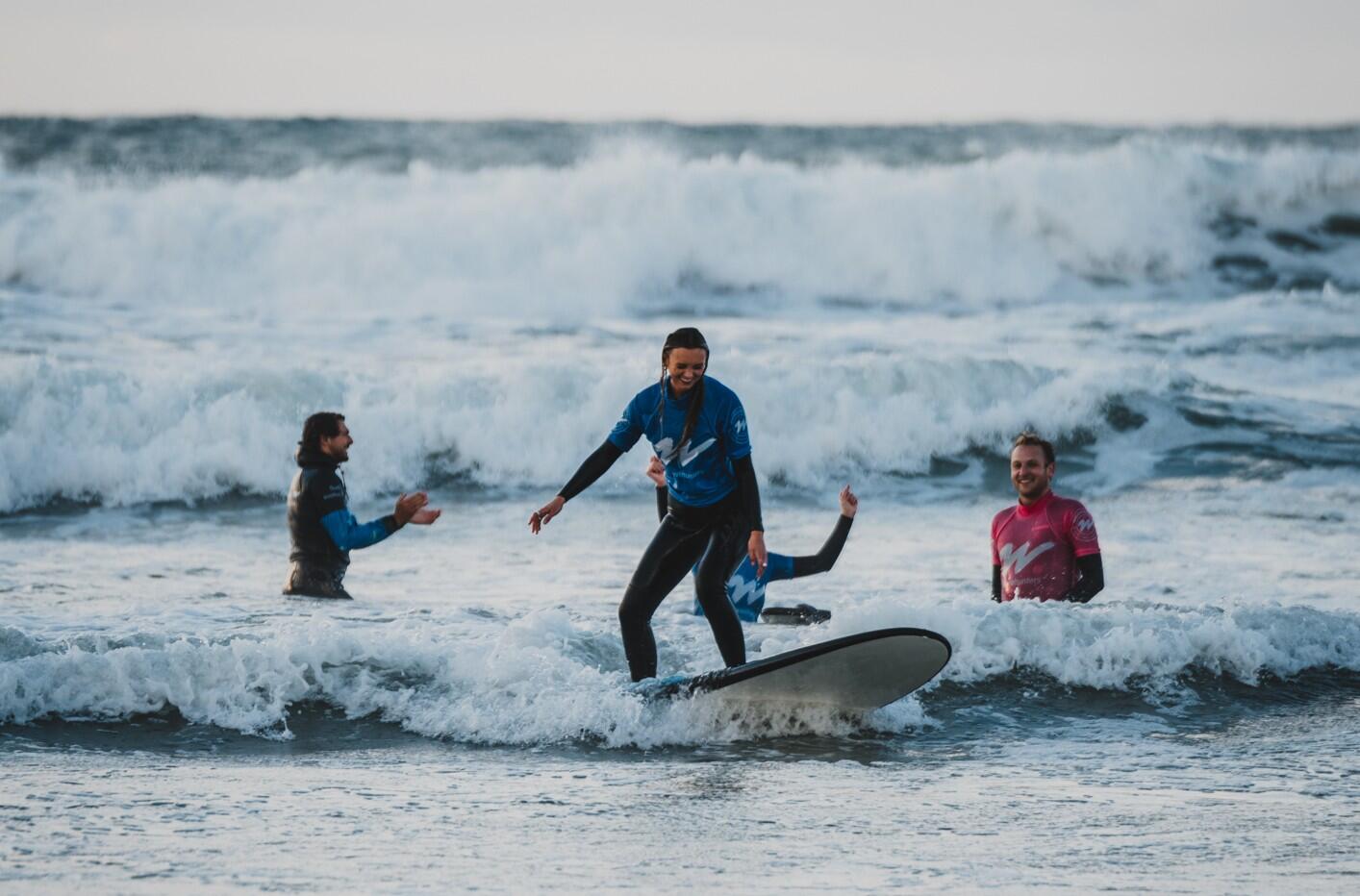 Woman smiling catching a wave on a surf lesson with Wavehunters