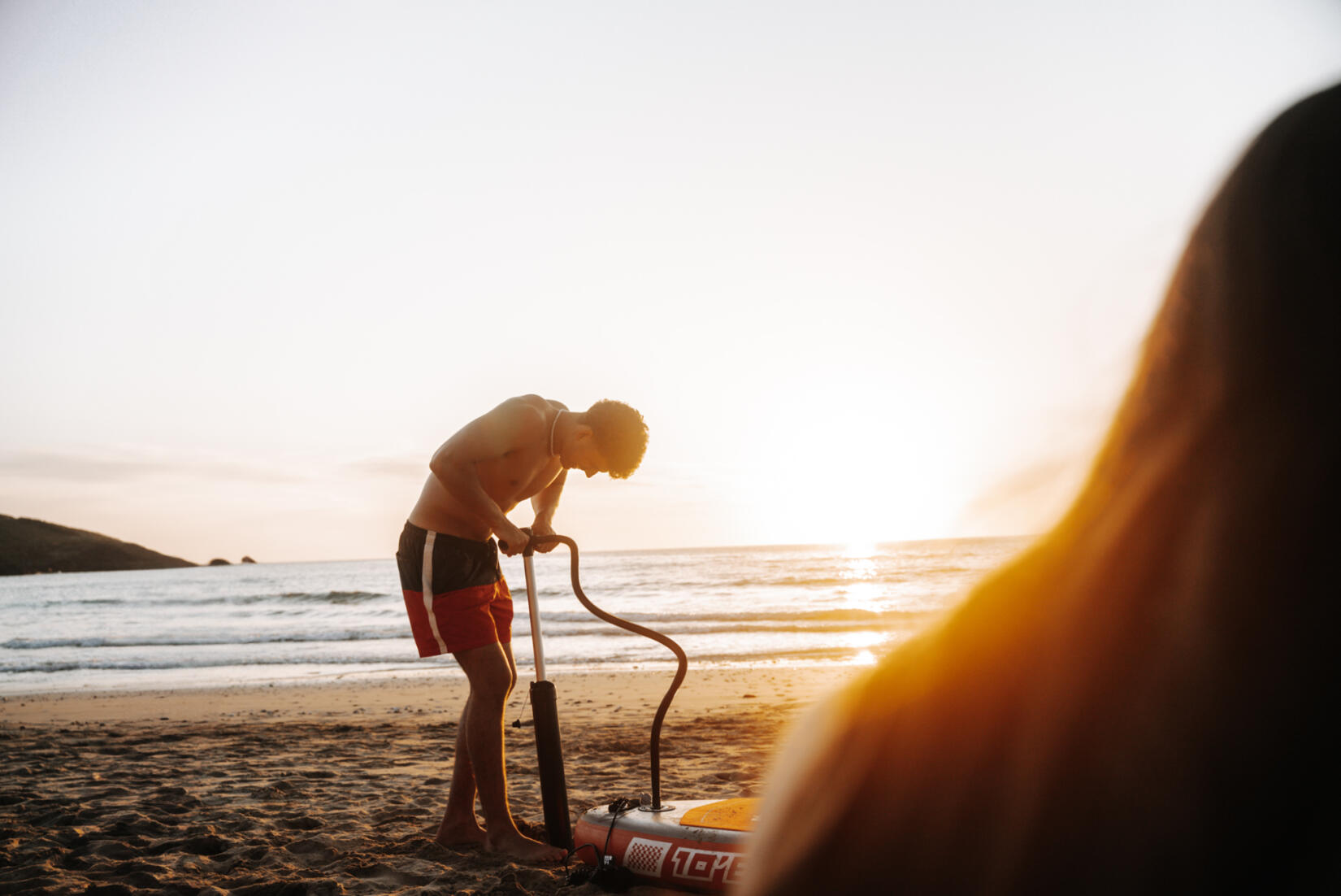 Man pumping up a paddleboard, Newquay