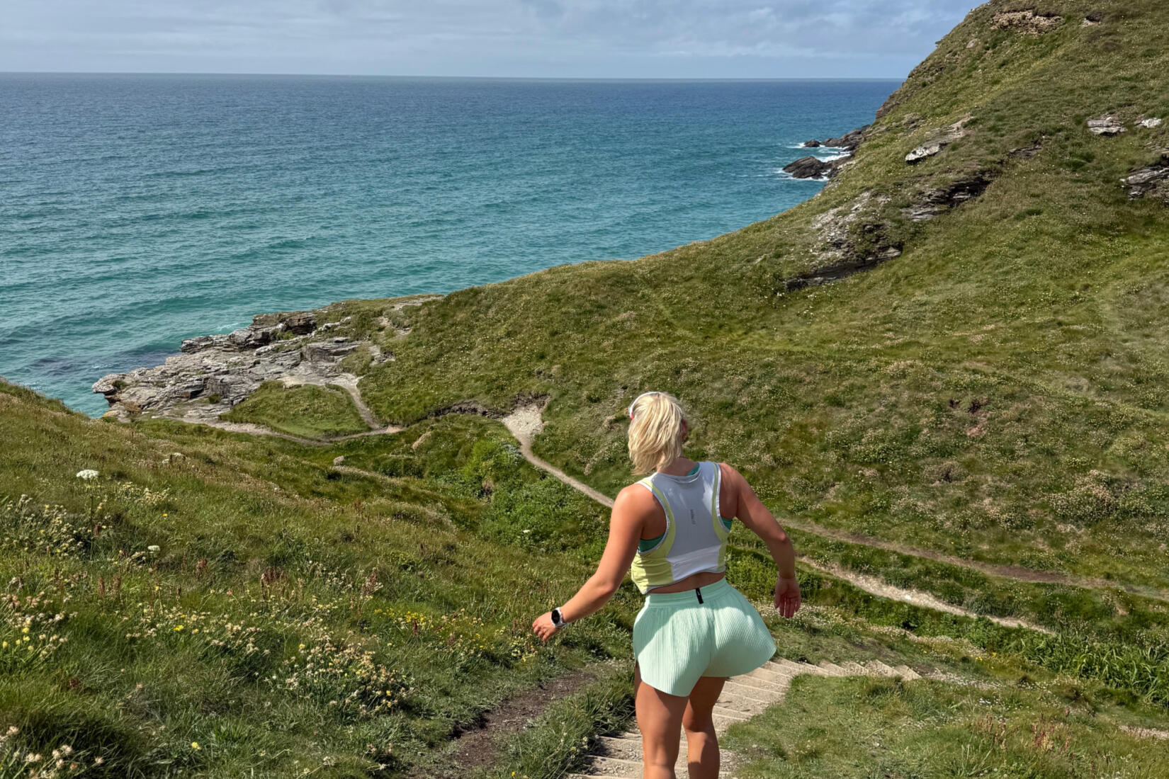 Woman running along the coast path from Porth