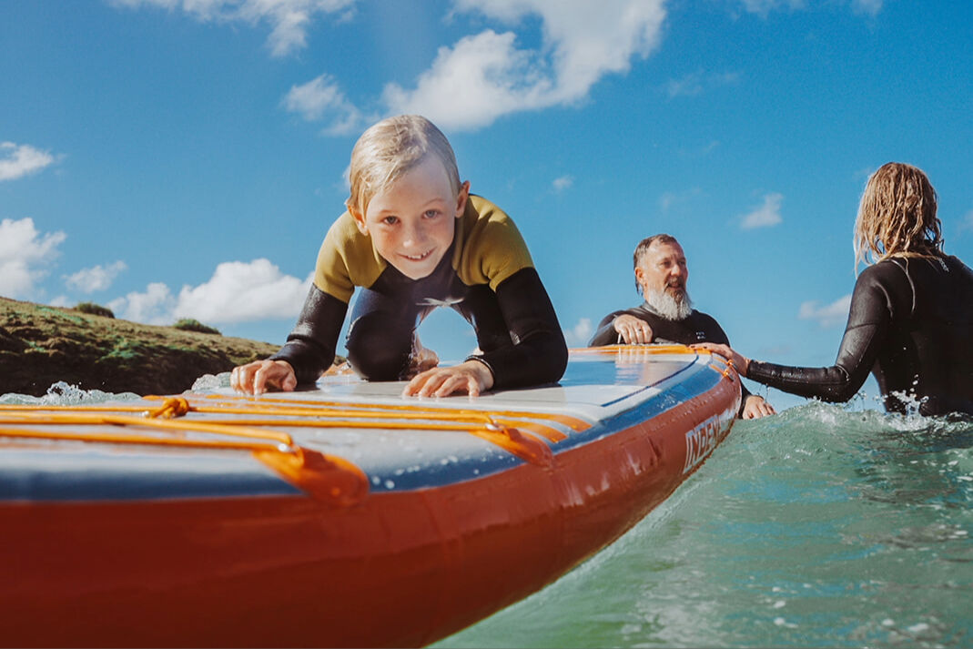Child on a SUP with parents in the water behind him